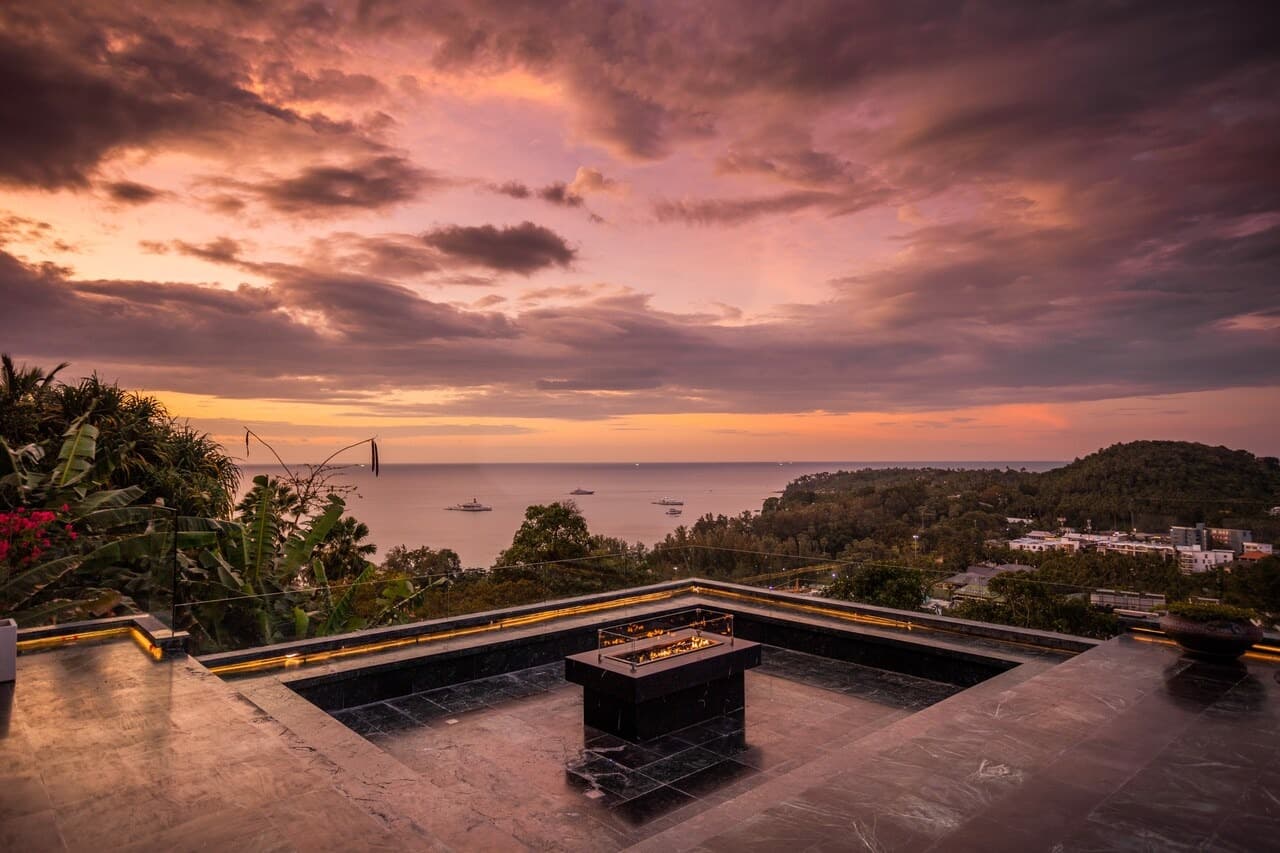 Rooftop fire pit terrace overlooking the bay under a fiery sunset sky